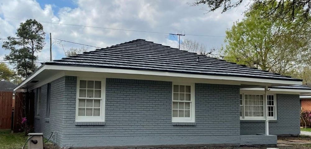 Side of the gray painted brick ranch with white window trim, fascia and porch post
