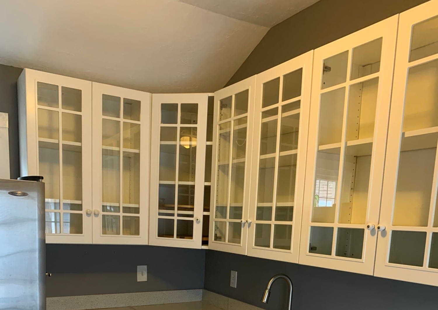 Bellaire kitchen with a run of white glass-front upper cabinets under a vaulted ceiling