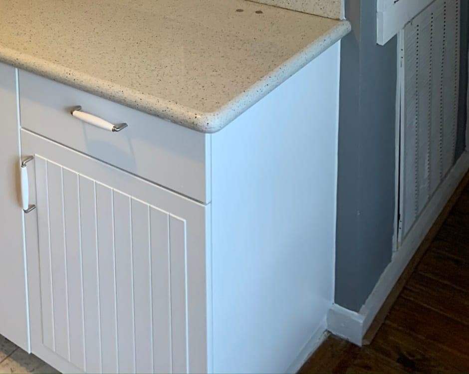 White beadboard base cabinet door and drawer at the end of the counter