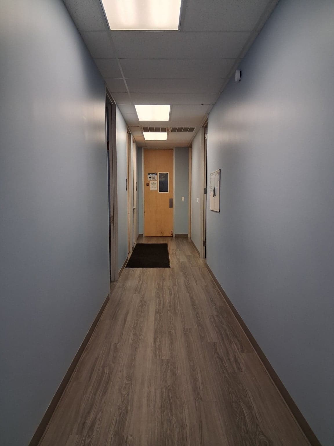 The same office hallway after painting, with clean soft-blue walls