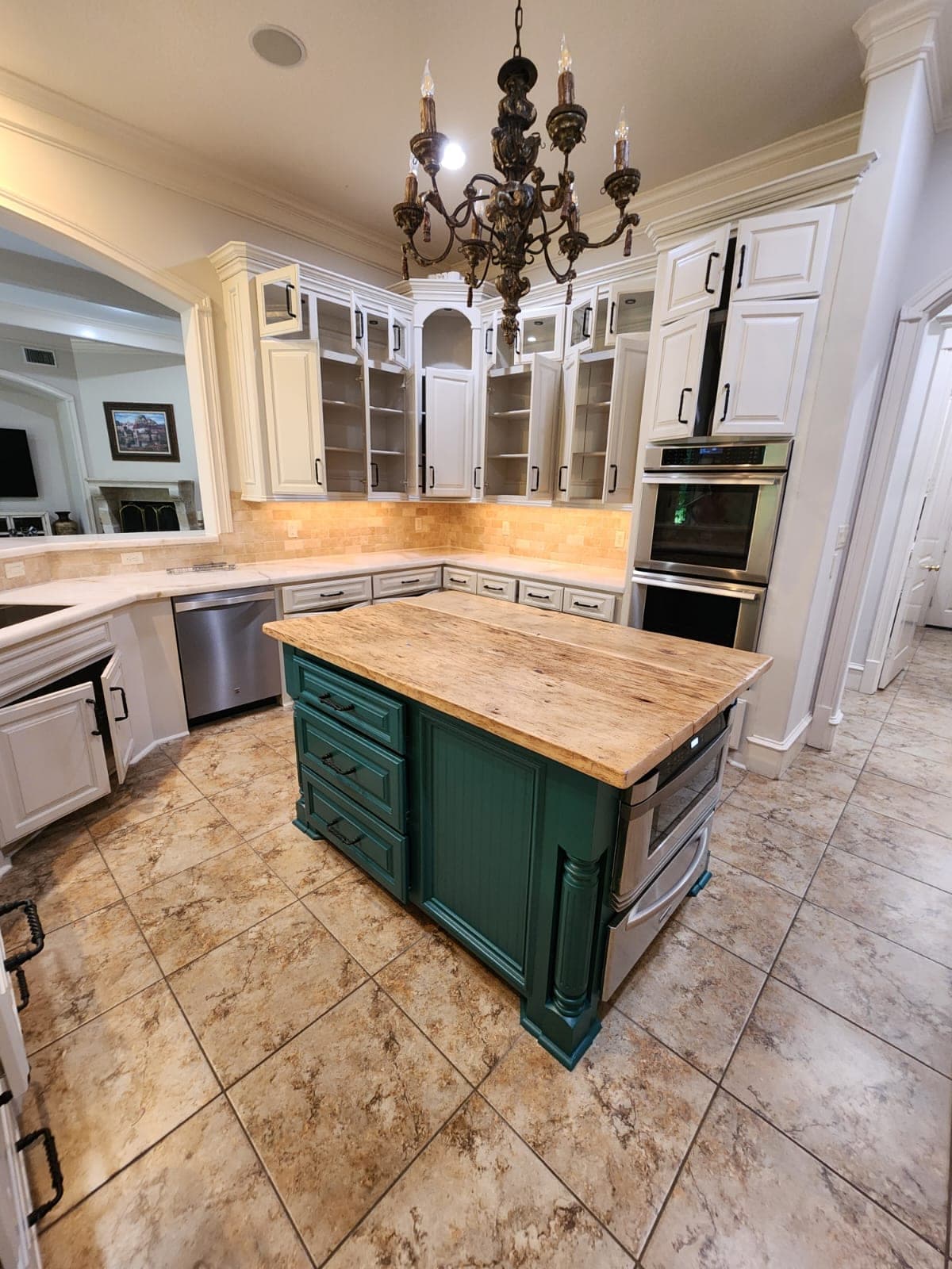 Teal island with fluted posts below white upper cabinets with glass doors