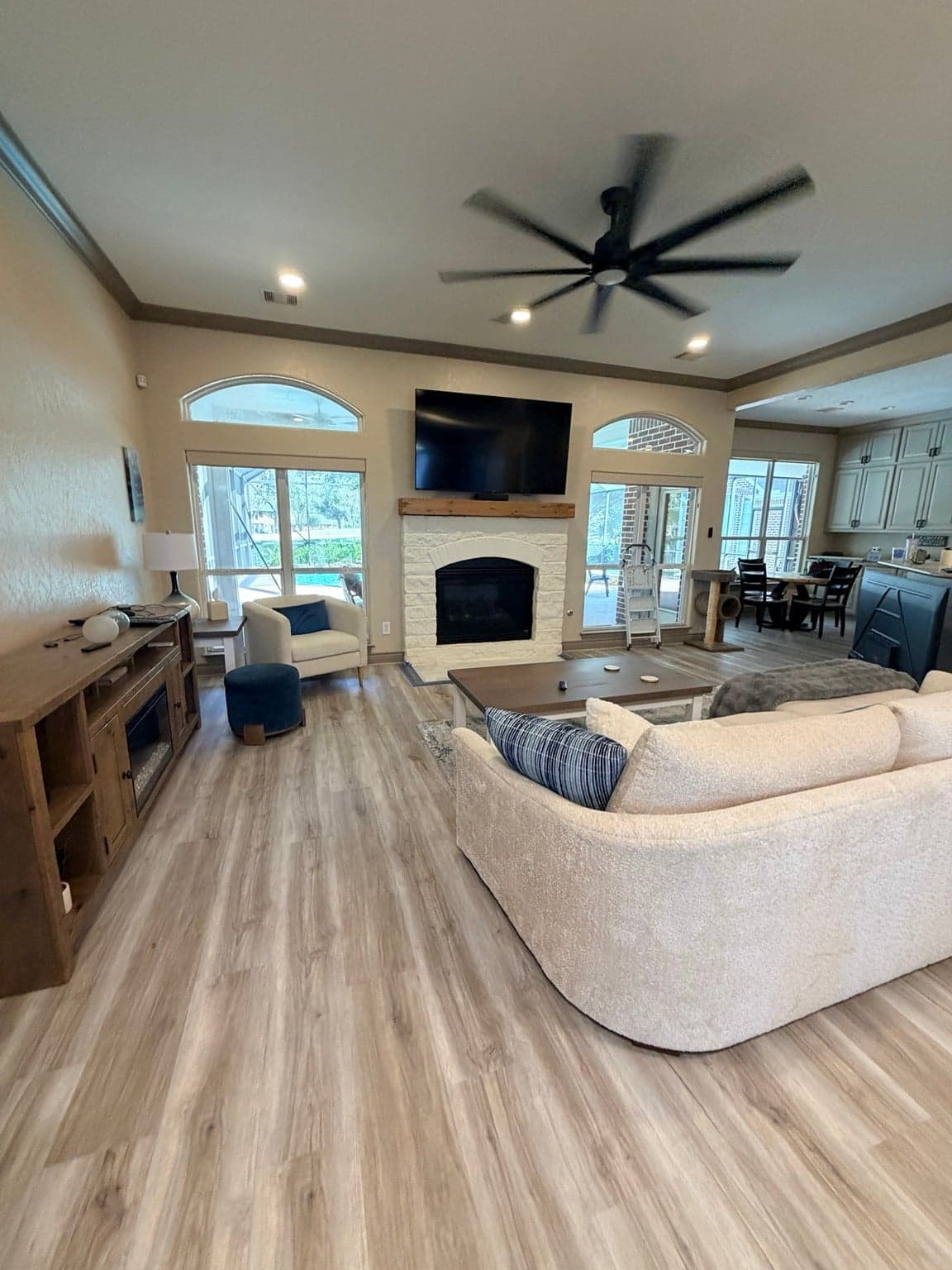 Fulshear living room with beige walls, taupe crown molding and baseboards, and a white stone fireplace