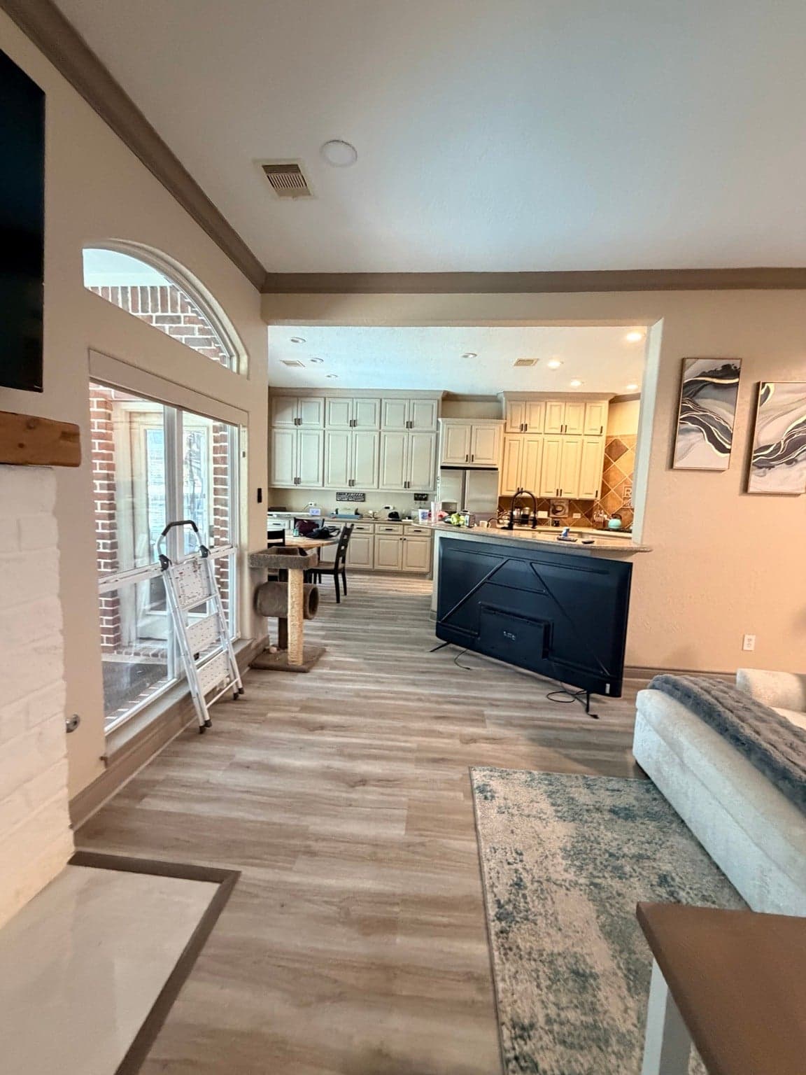 View from the living room to the kitchen, with beige walls and taupe crown molding