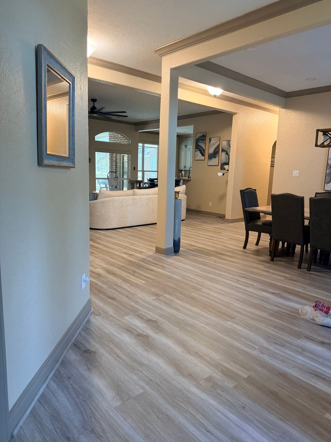 Entry hall opening to the living and dining areas, with taupe trim on columns and baseboards