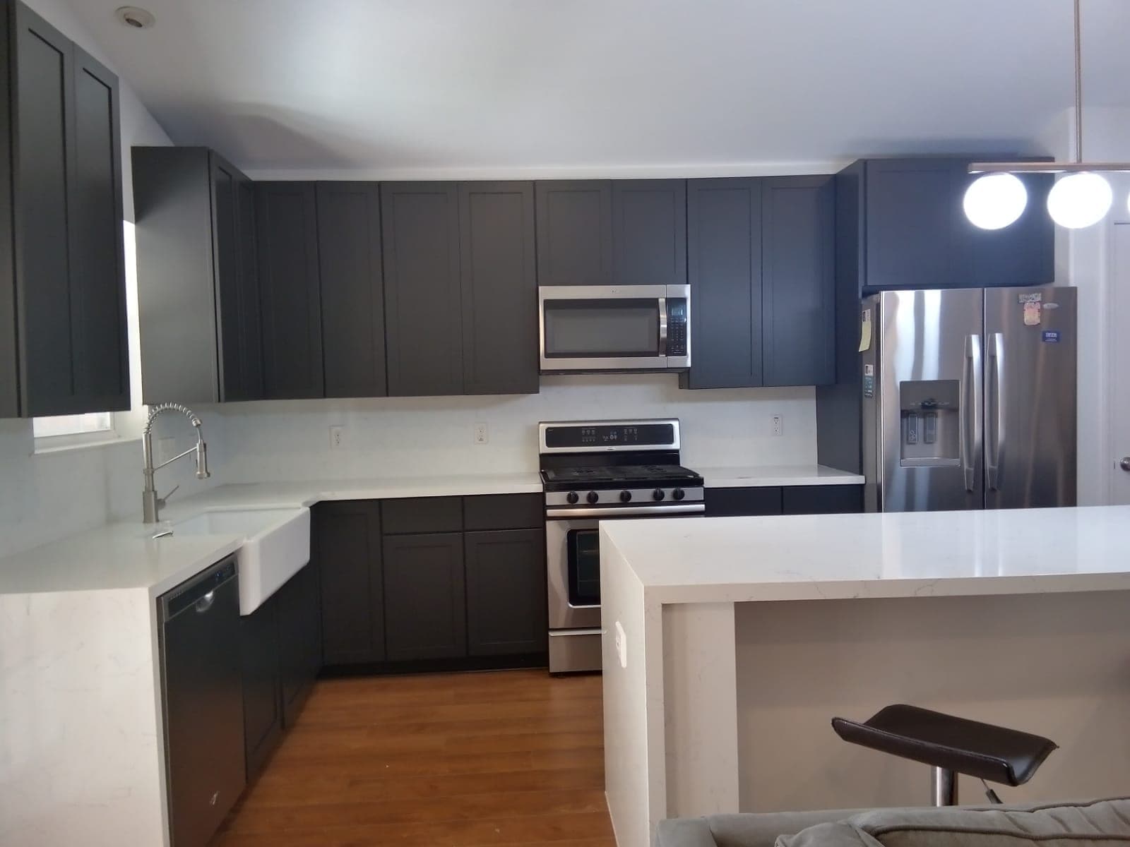 Heights kitchen with charcoal shaker upper and lower cabinets, white counters and a white waterfall island