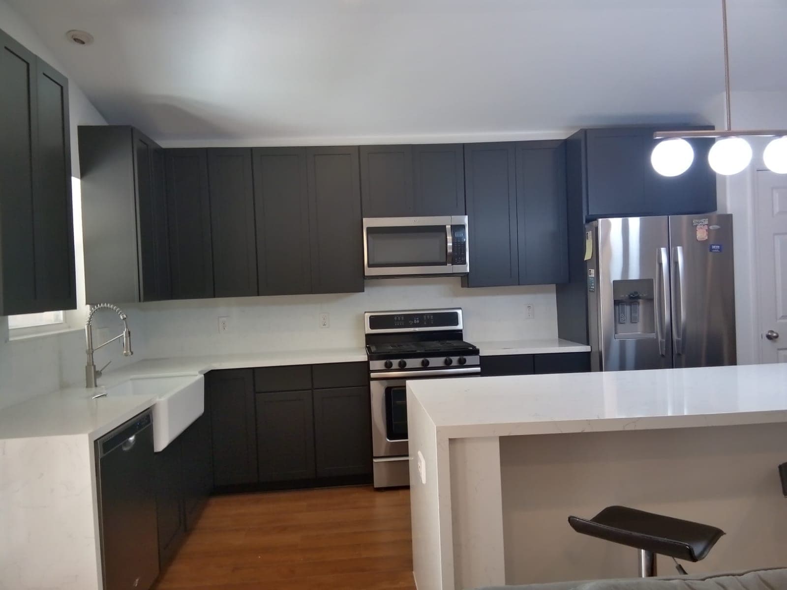 Charcoal shaker cabinets around the farmhouse sink, range and refrigerator