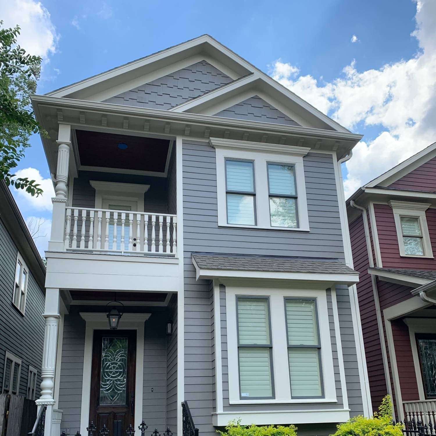 Two-story Heights home with gray lap siding, shingle-style gables and cream trim, balcony and columns