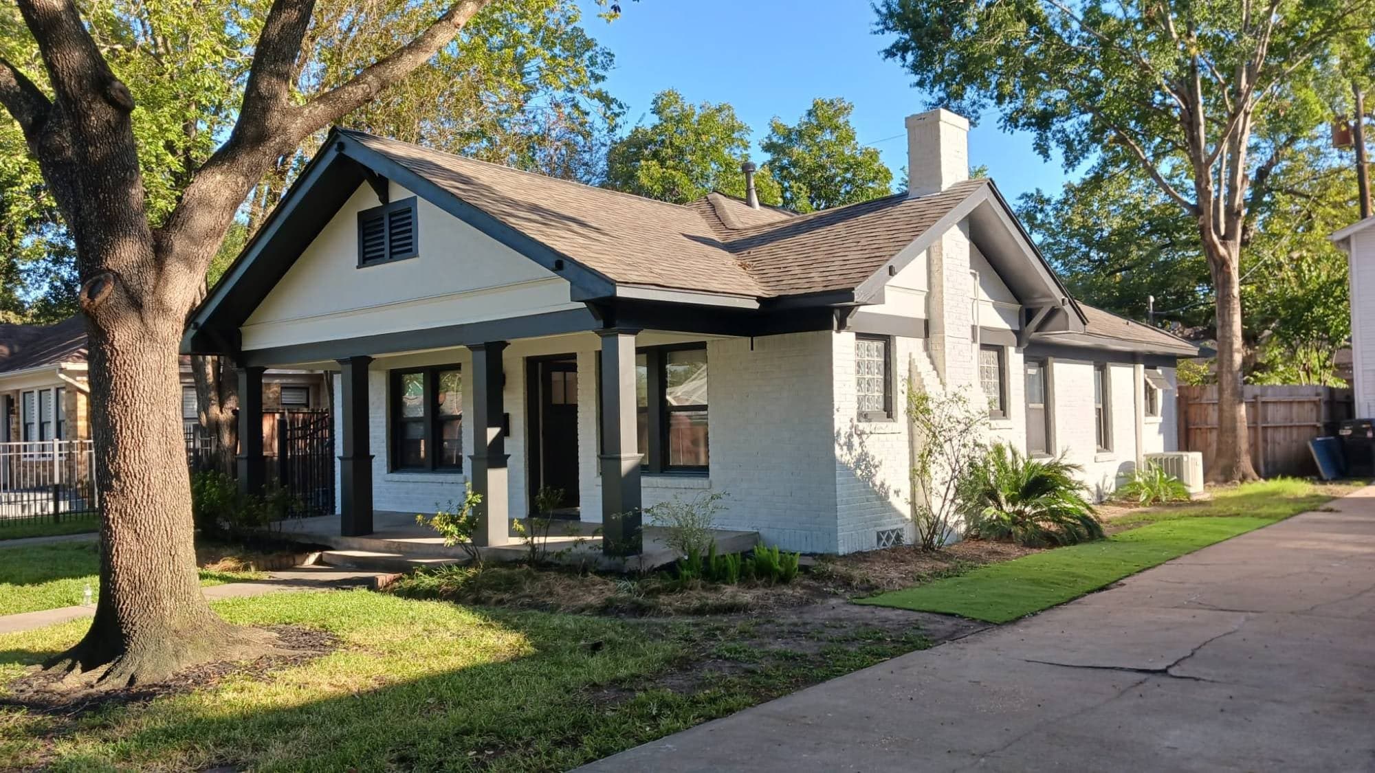 Heights bungalow with white painted brick, a white gable and black porch columns, fascia and window trim