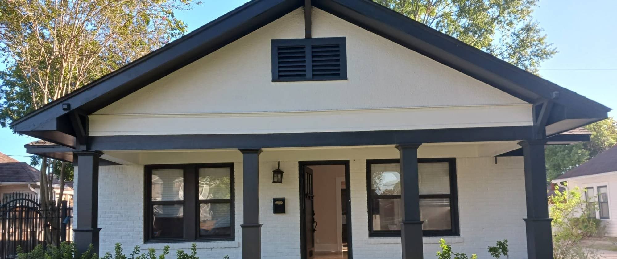 Front of the bungalow: white painted brick and gable with black columns, beams and window frames