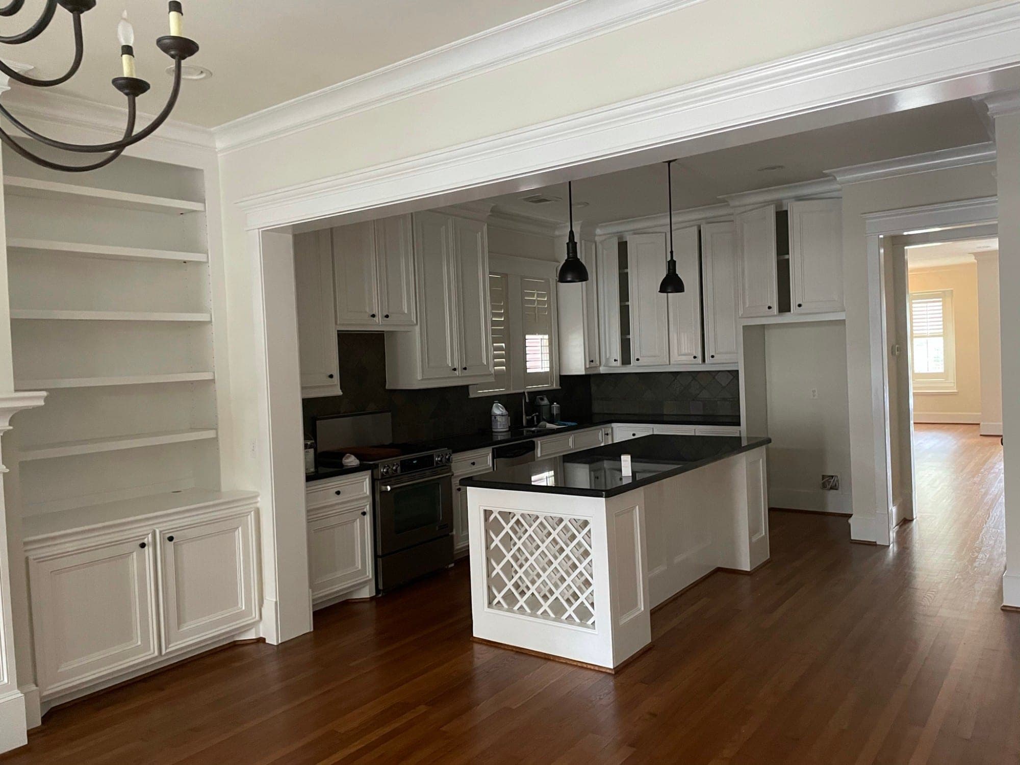 Heights kitchen with white beadboard cabinets and black counters, a lattice-end island and white built-in shelves