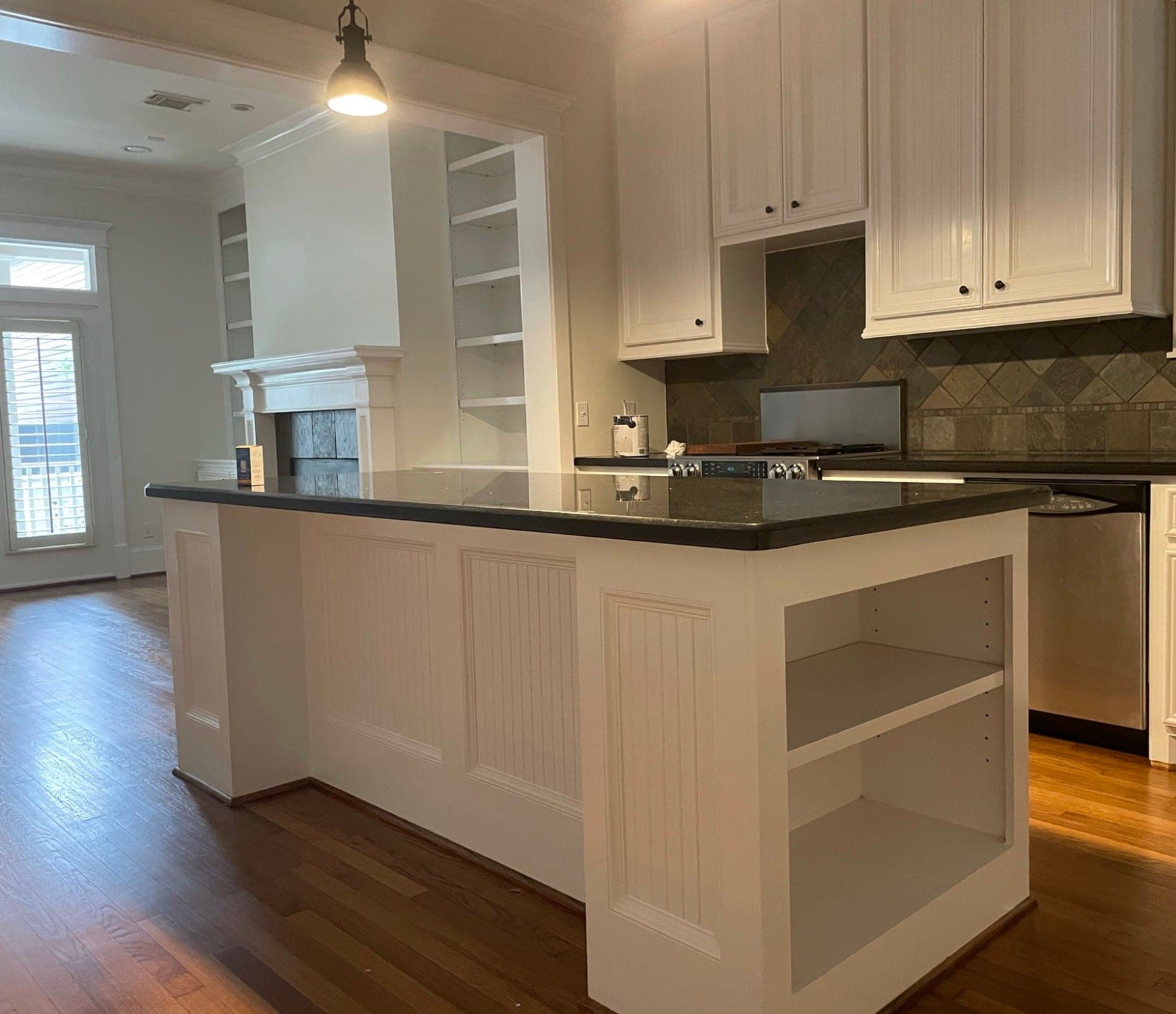White beadboard island with open end shelves under a black granite top