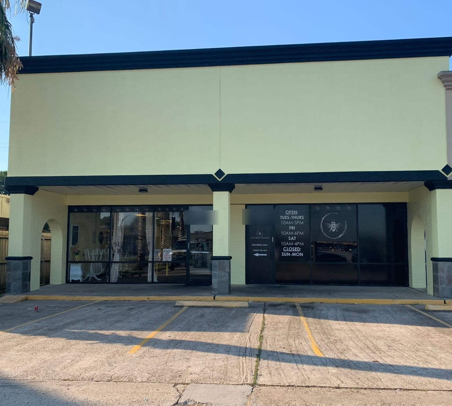 Front view of the yellow-green storefront with black cornice, black diamond accents and stone column bases