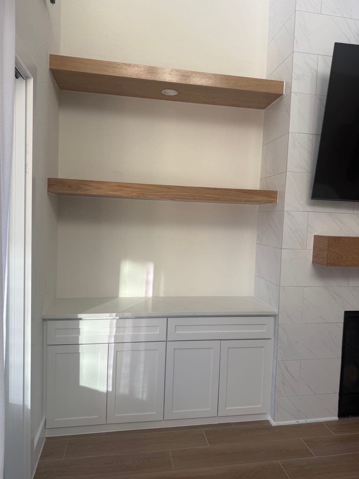White shaker built-in cabinet with a stone top and two oak floating shelves