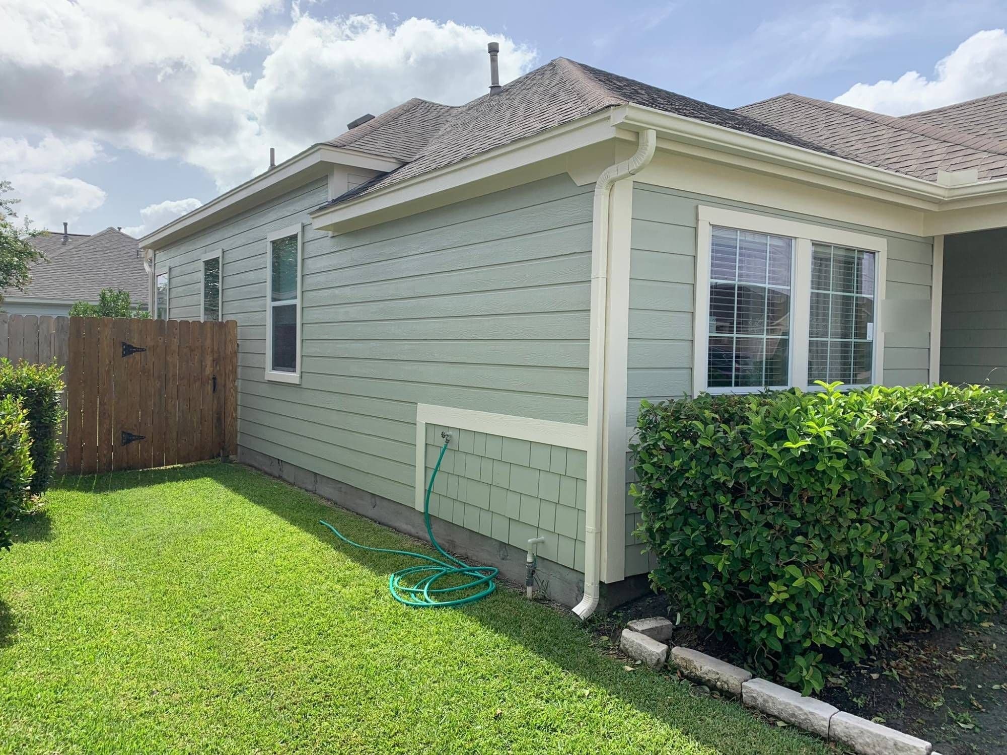 Pearland home with sage-green lap siding, a shingle-siding accent panel, cream window trim and cream downspouts