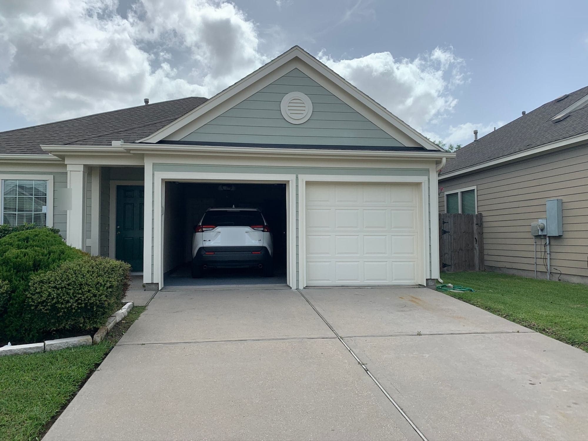 Front of the home with a sage-green gable, cream trim around the garage openings and a cream garage door