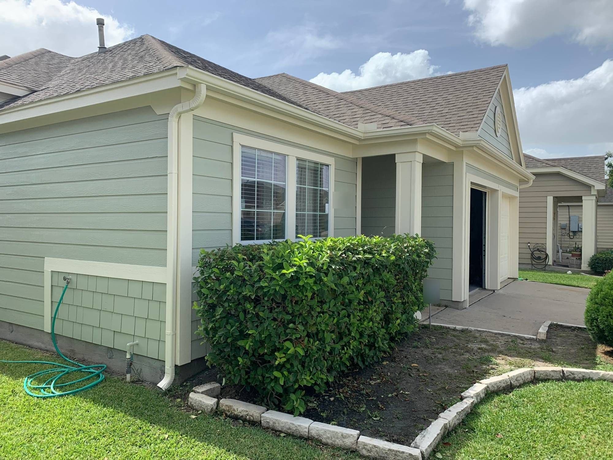 Front corner with sage-green siding, cream trim and columns at the entry