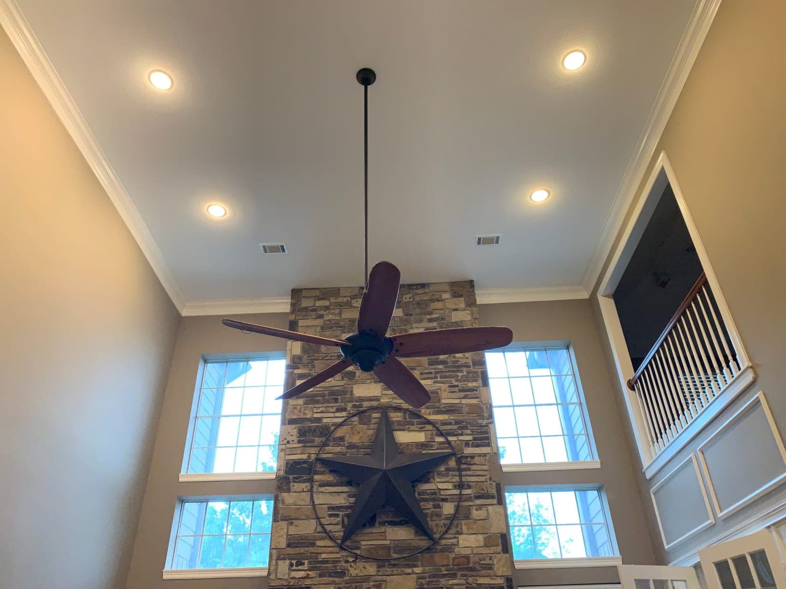 Two-story ceiling and white crown molding above the great room fireplace and tall windows