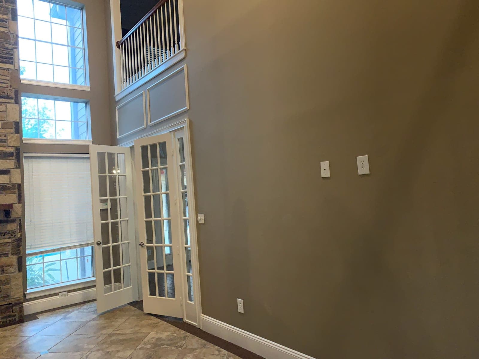 Tall taupe wall beside white French doors and the upstairs overlook