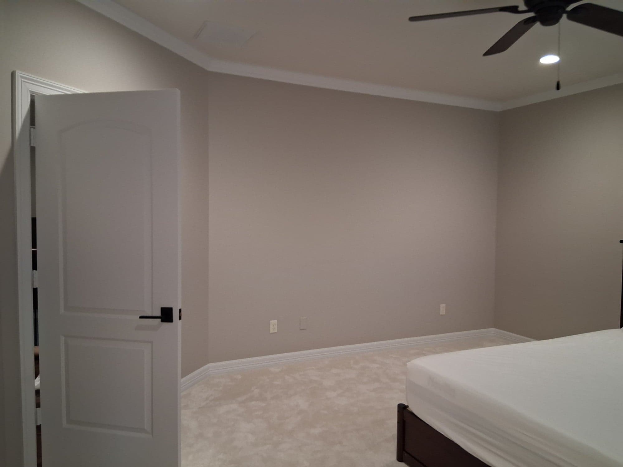 Richmond bedroom with freshly painted greige walls, white crown molding, baseboards and door