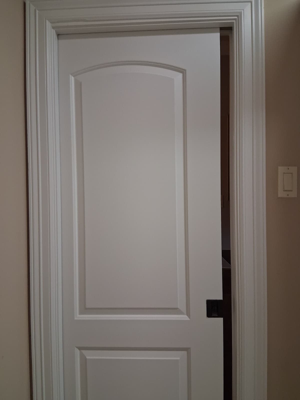 Close-up of a white two-panel pocket door and casing against greige walls