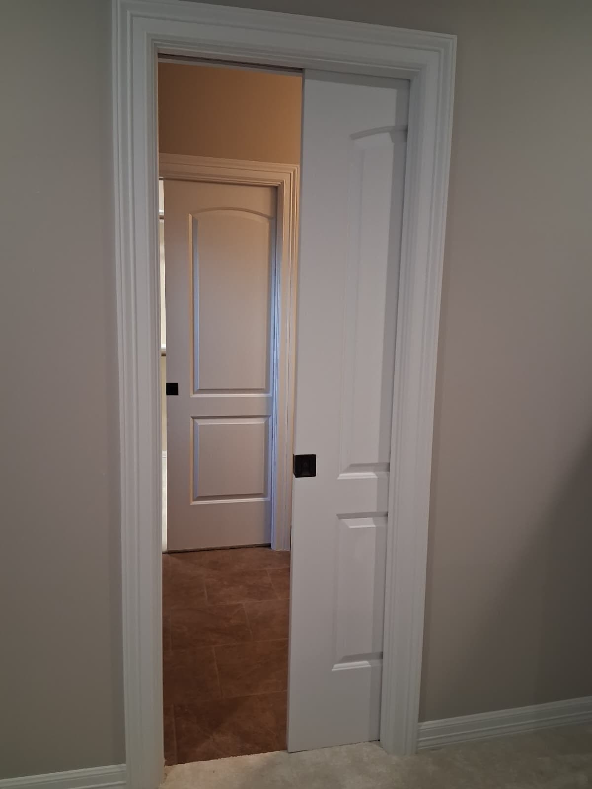 White pocket door and casing opening to a tiled hallway
