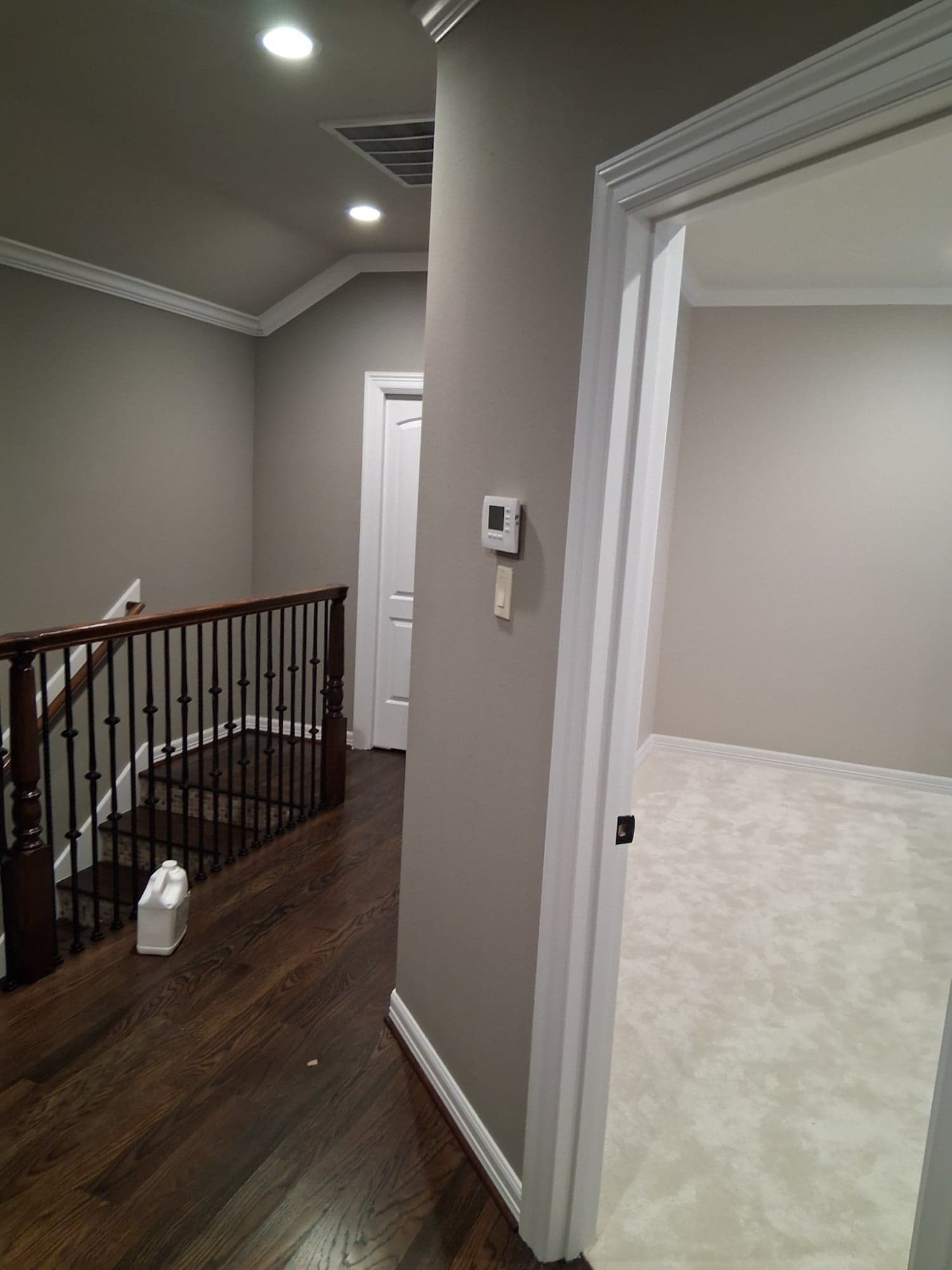 Upstairs landing with greige walls and white door casing opening into a bedroom
