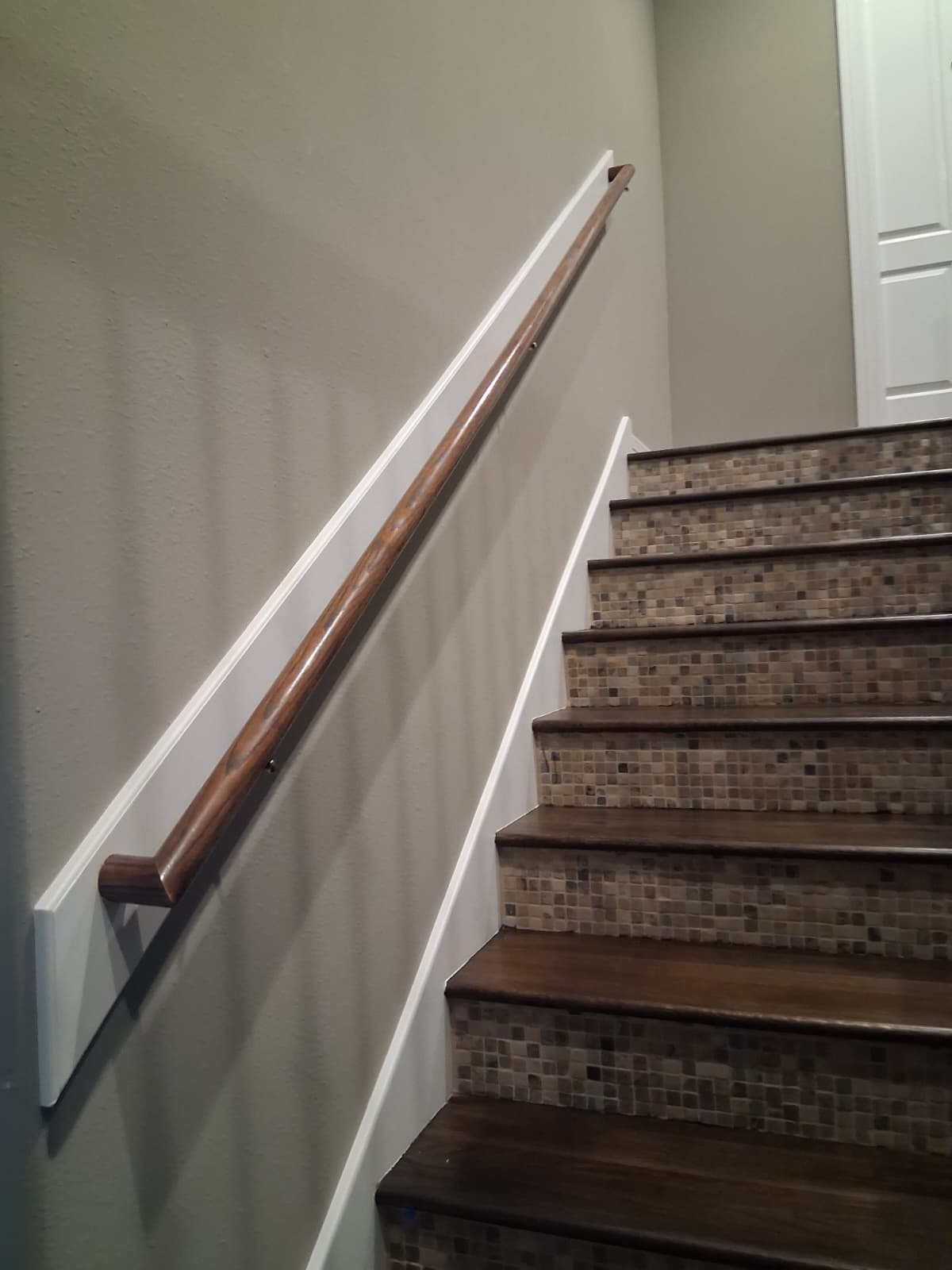 Stairwell wall with a white handrail backer board and greige walls