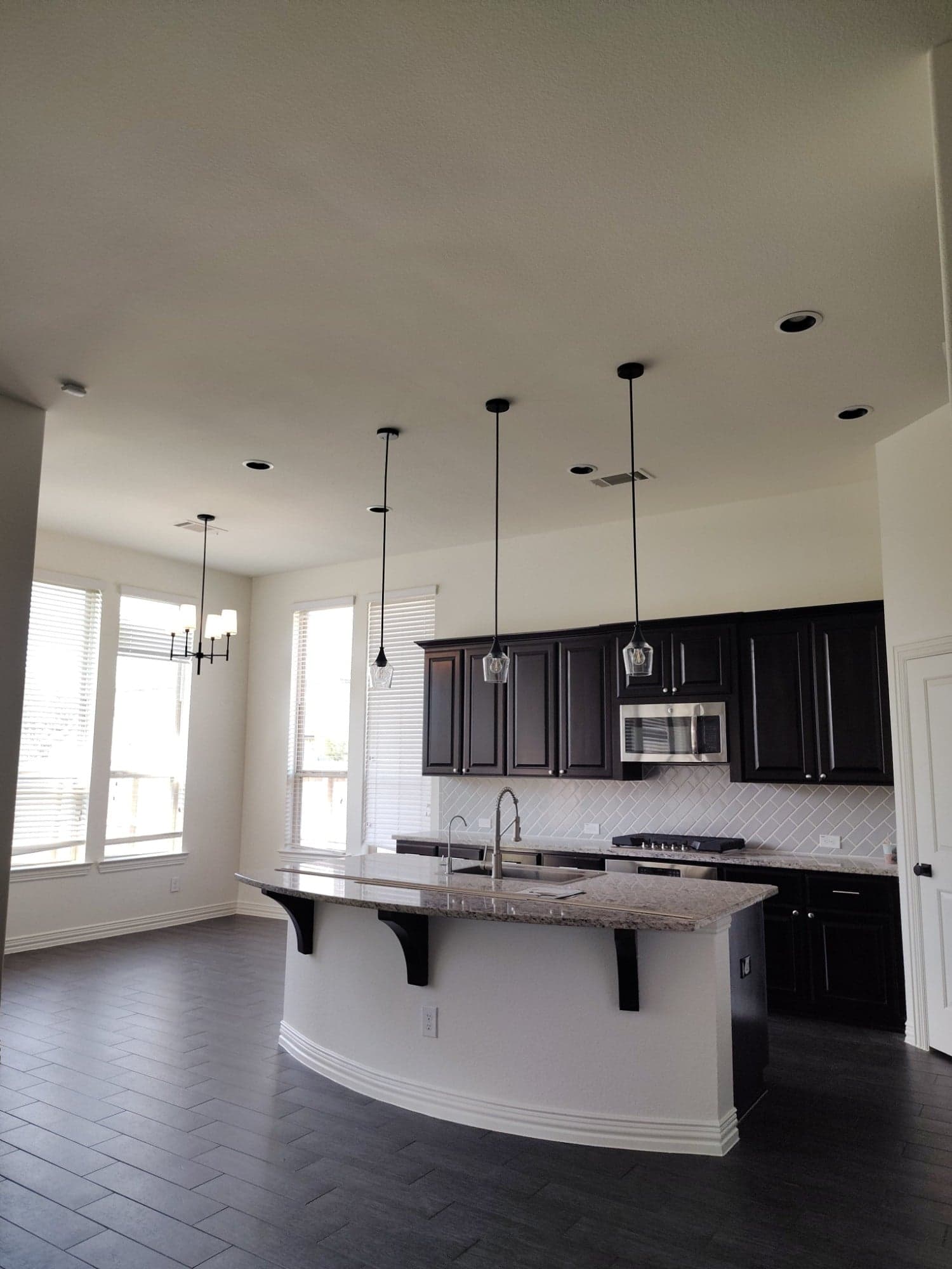 Kitchen and breakfast area with white walls and a white island base beside dark cabinets