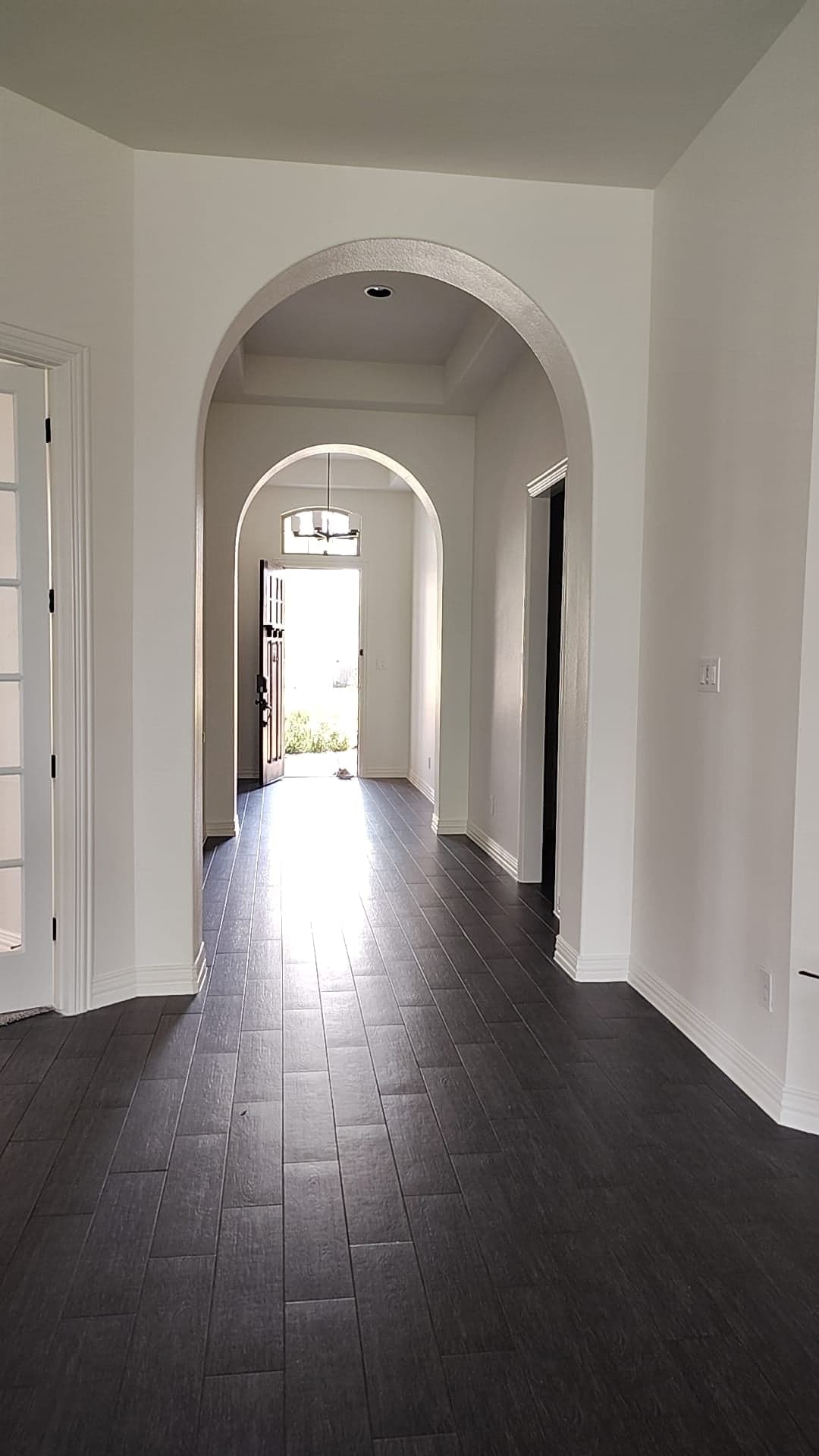 Arched entry hall leading to the front door, with white walls and baseboards