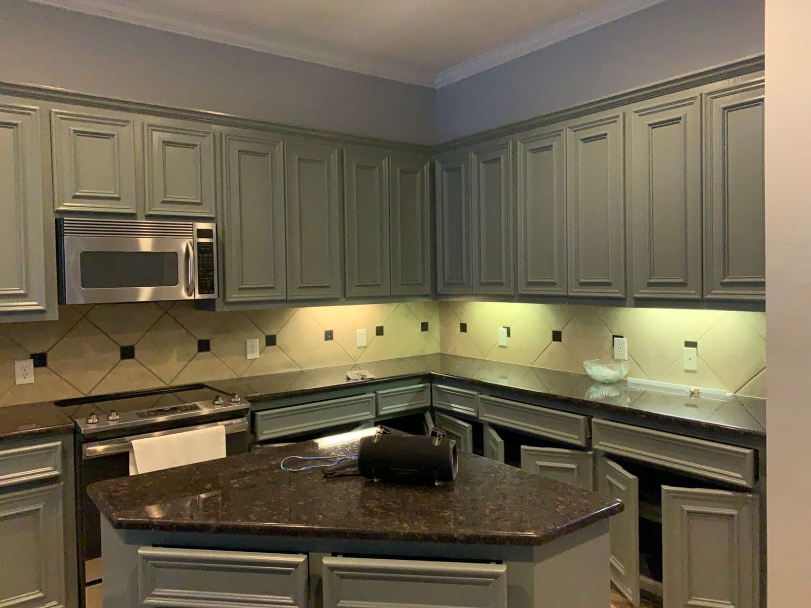 Richmond kitchen with raised-panel upper and lower cabinets painted sage green under dark granite counters