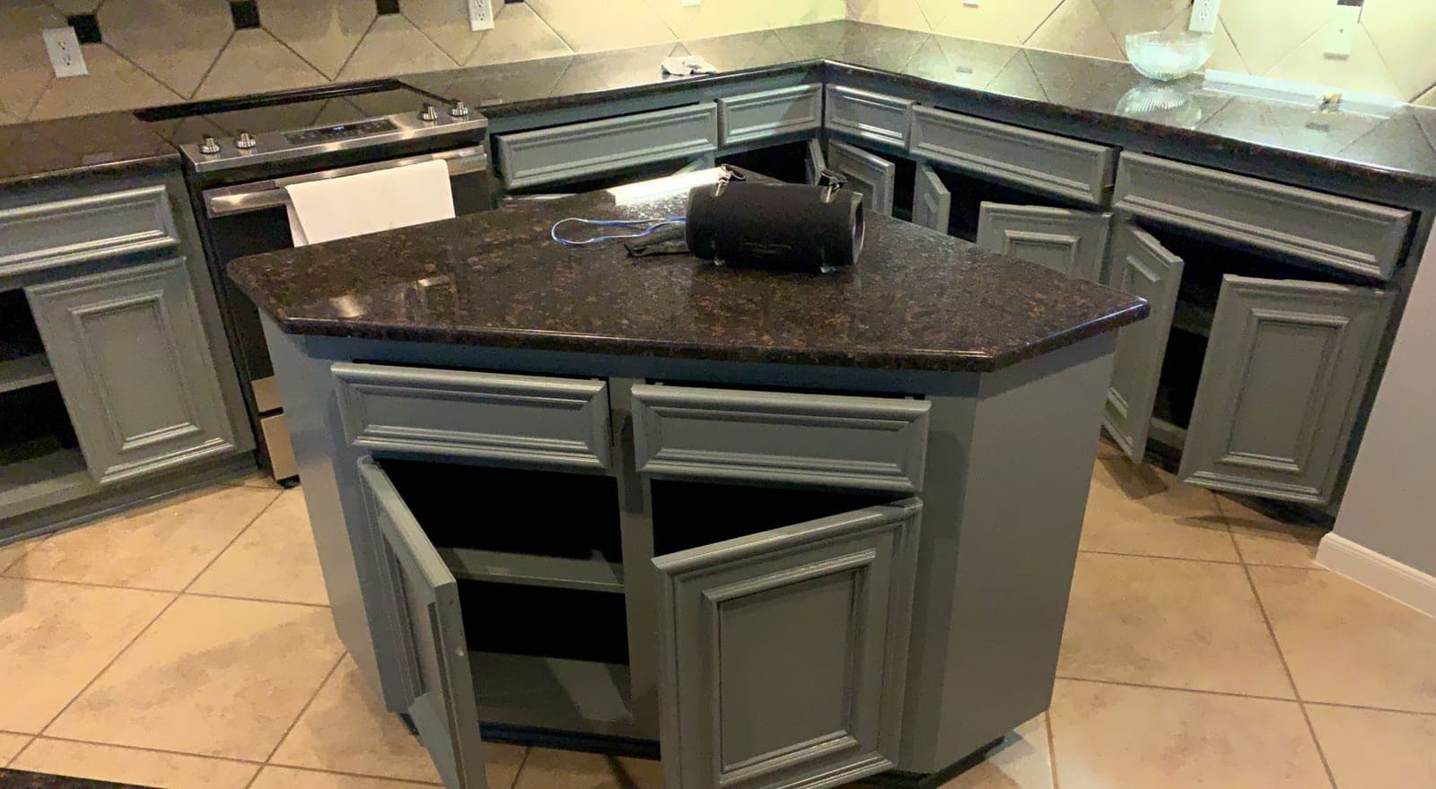 Angled kitchen island with raised-panel doors and drawers painted sage green