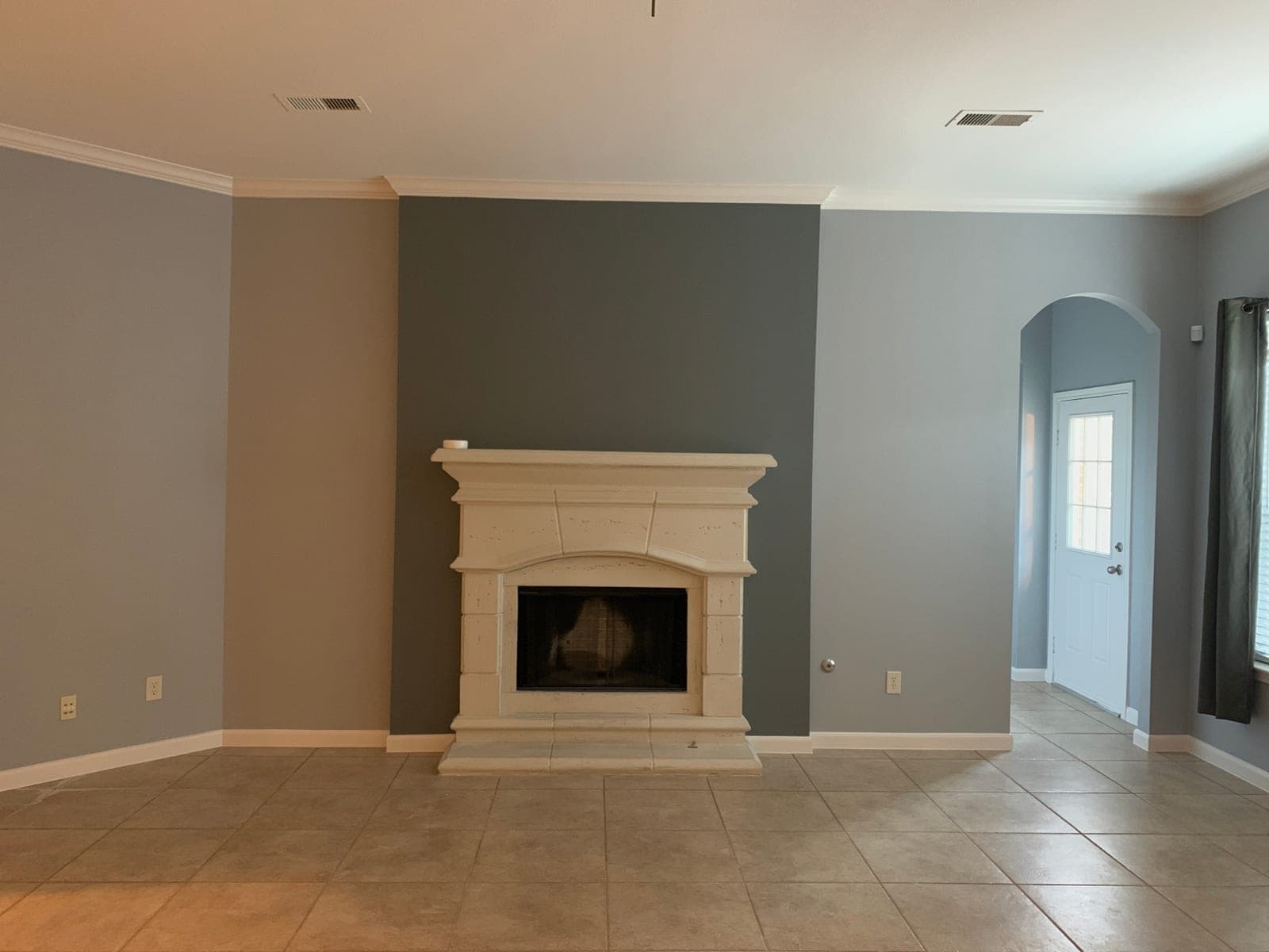 Living room with light gray walls, a dark gray accent wall behind the fireplace and white crown molding