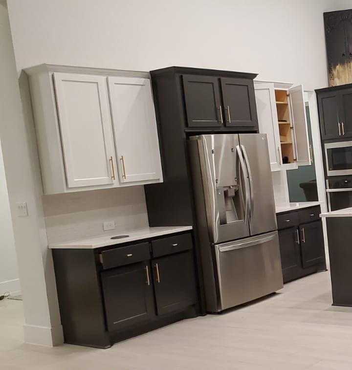 White upper cabinets beside near-black tall cabinets around the refrigerator