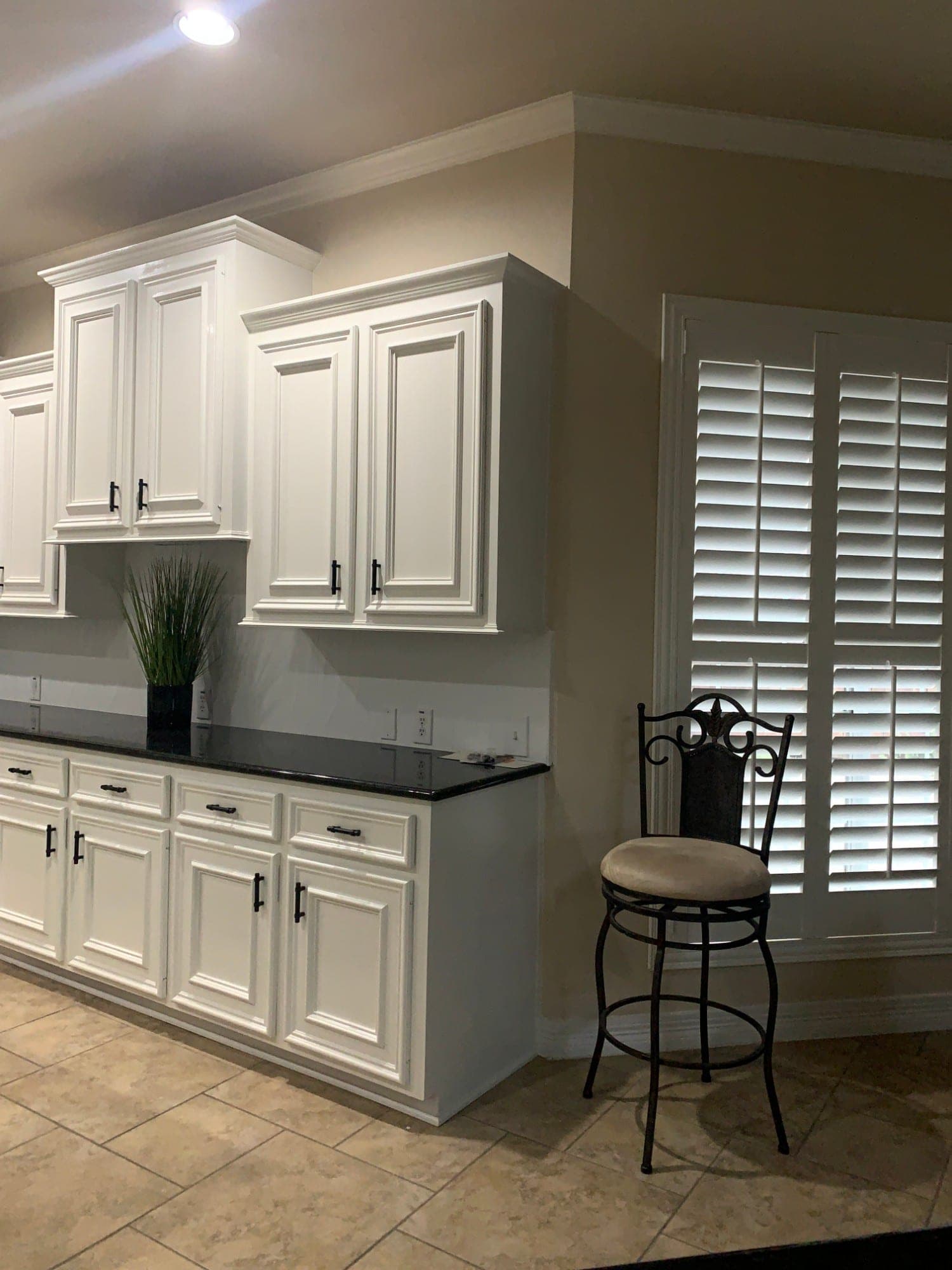 Sienna kitchen wall of white raised-panel cabinets with black bar pulls and a black granite counter