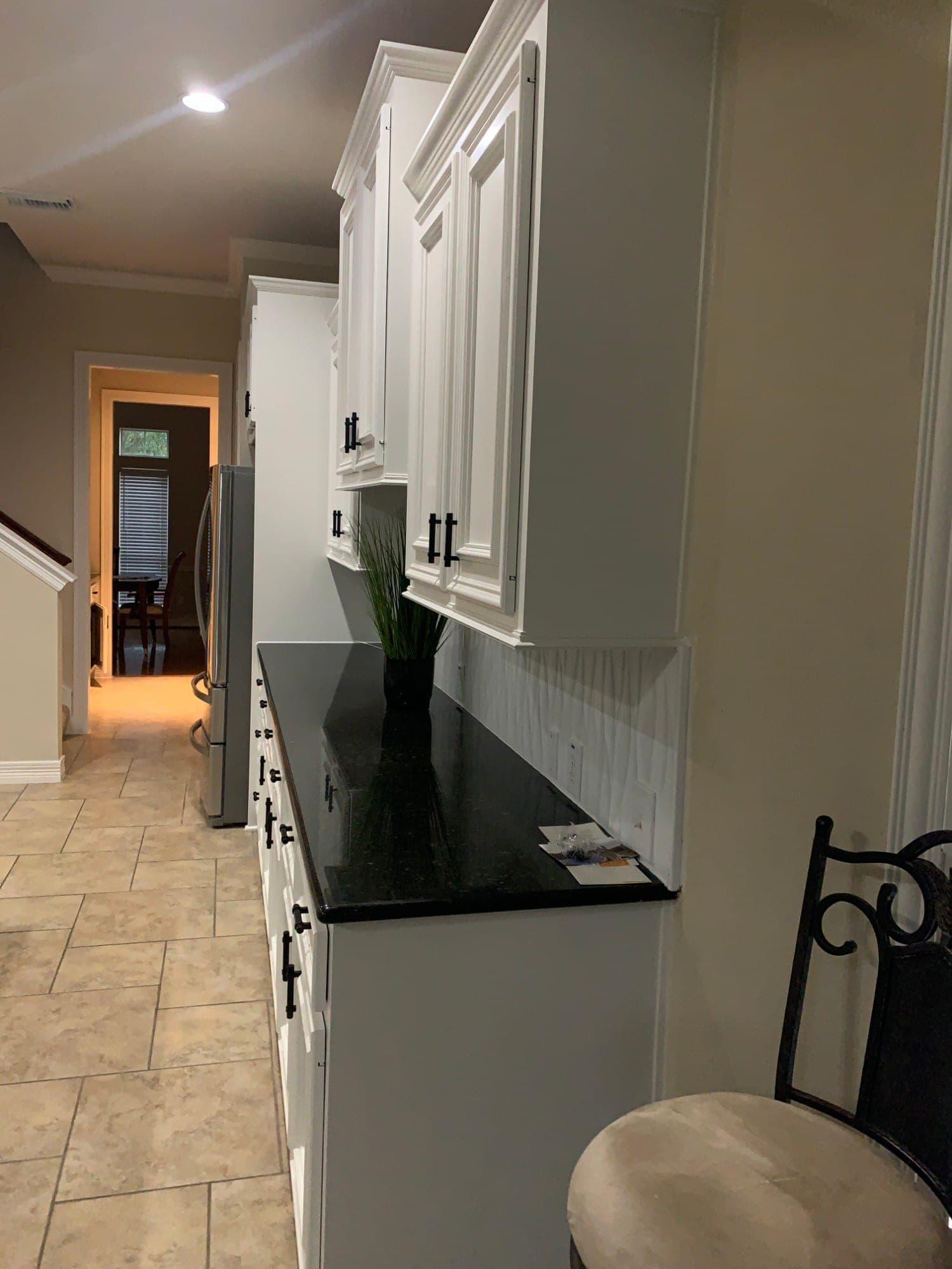 Long run of white upper and lower cabinets along the kitchen wall toward the hallway
