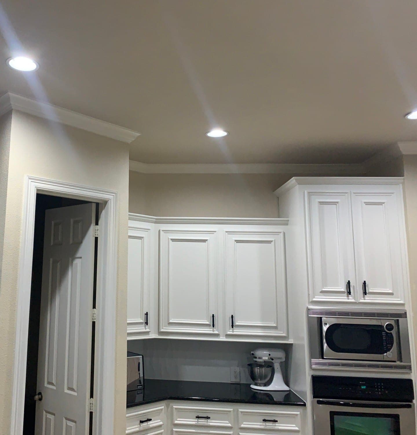 White upper cabinets with crown molding around the corner and above the wall oven