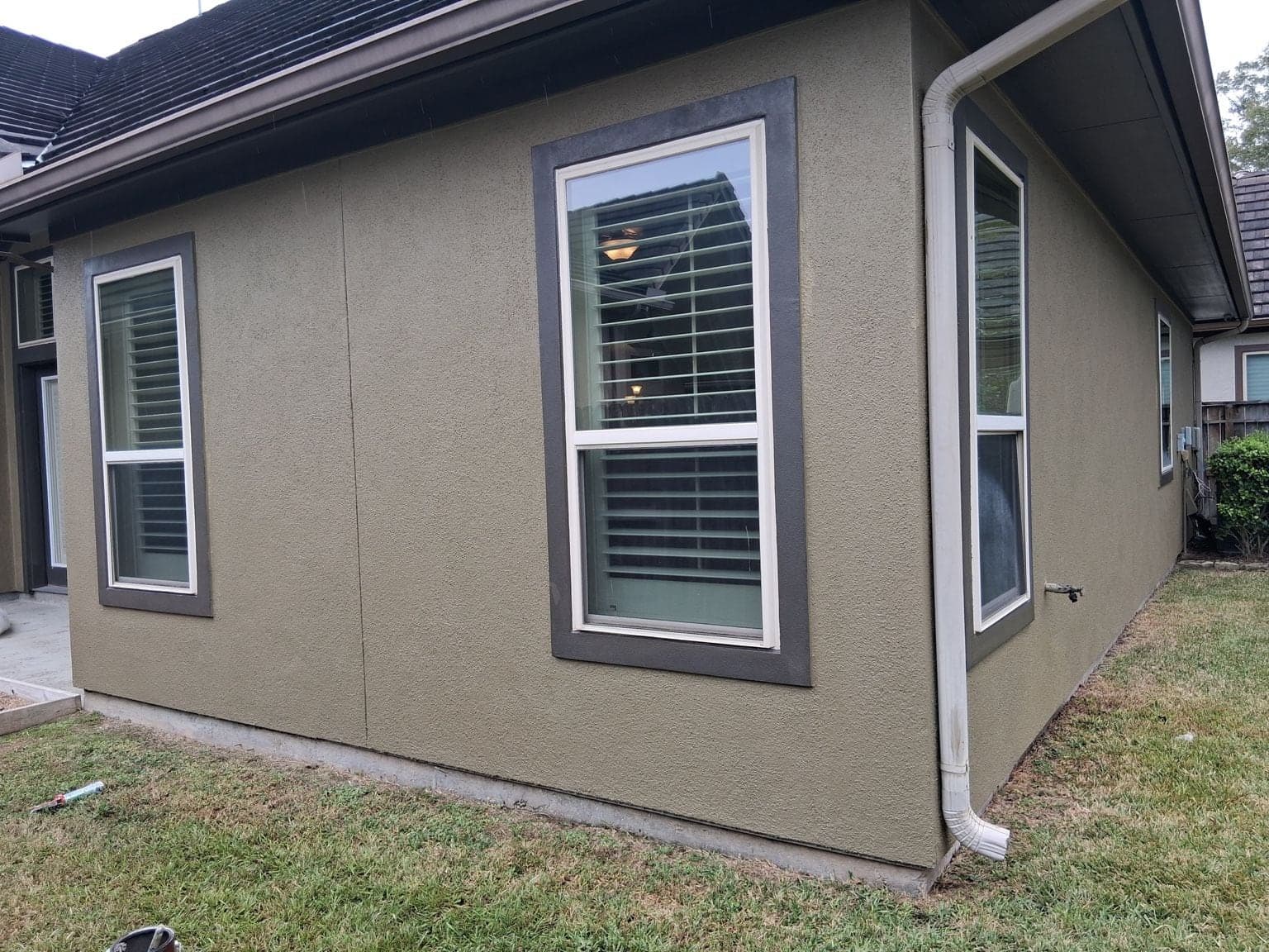 Rear corner of the home with olive-green stucco and wide dark brown window surrounds