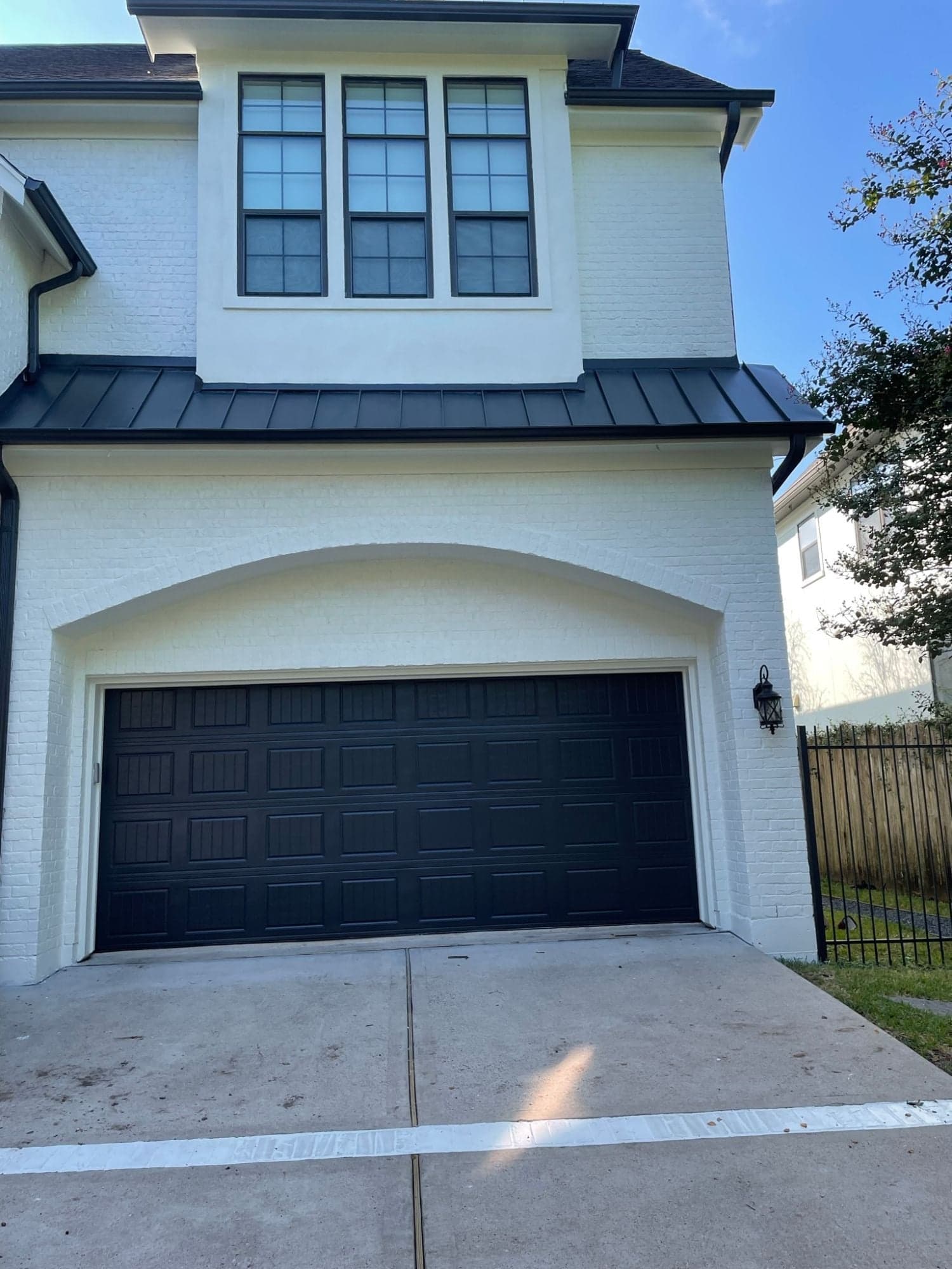 Garage elevation with white painted brick around an arched opening and a black garage door
