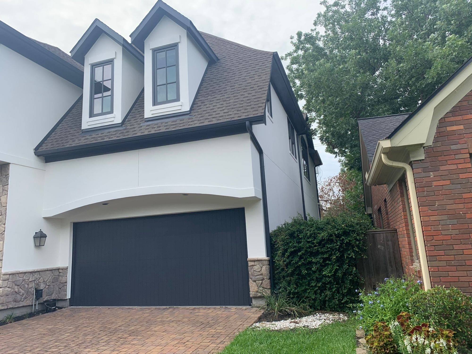 Side elevation of the white stucco garage wing with dark gutters and downspouts