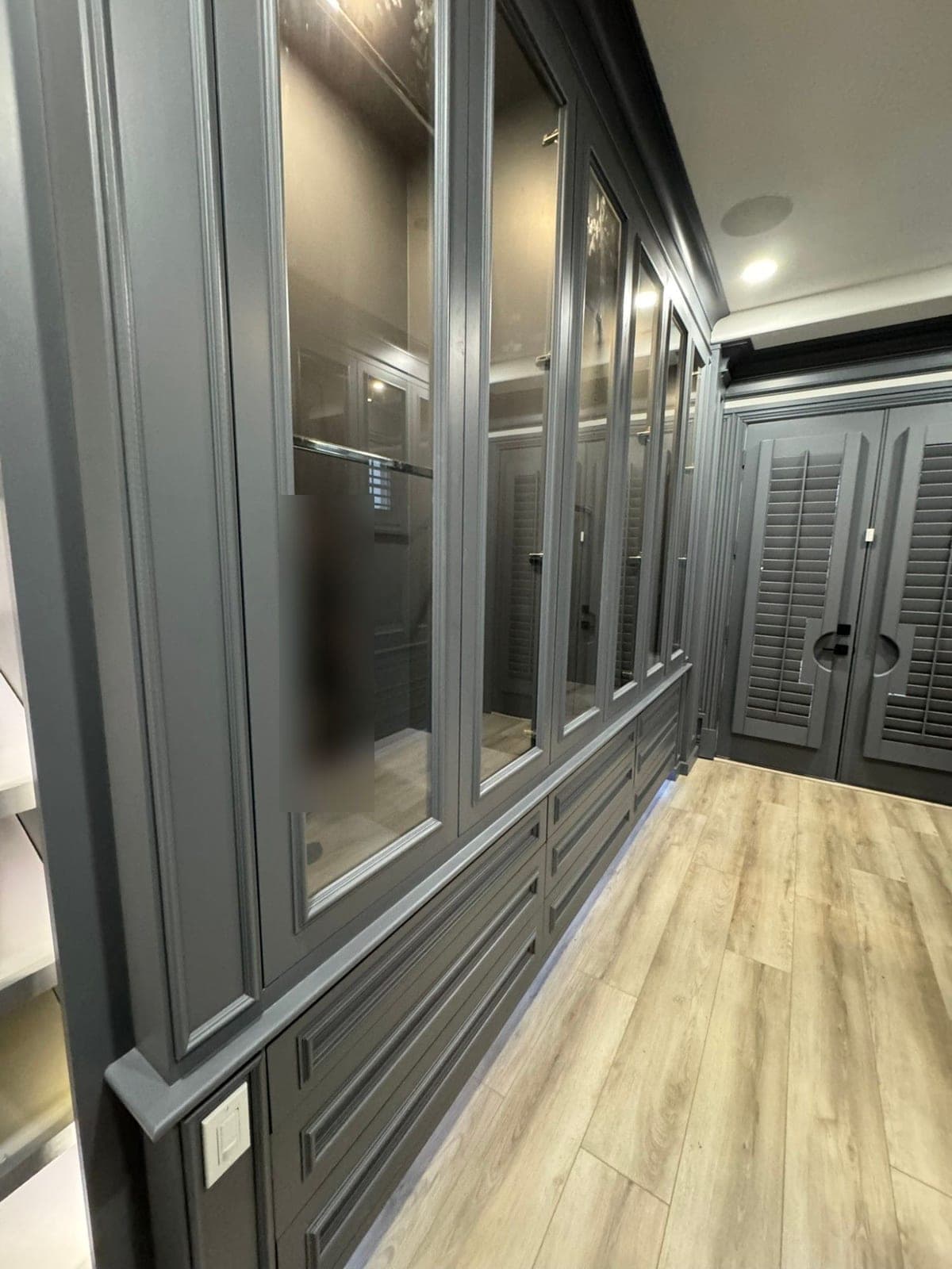 Long run of charcoal gray closet cabinets leading to gray double doors
