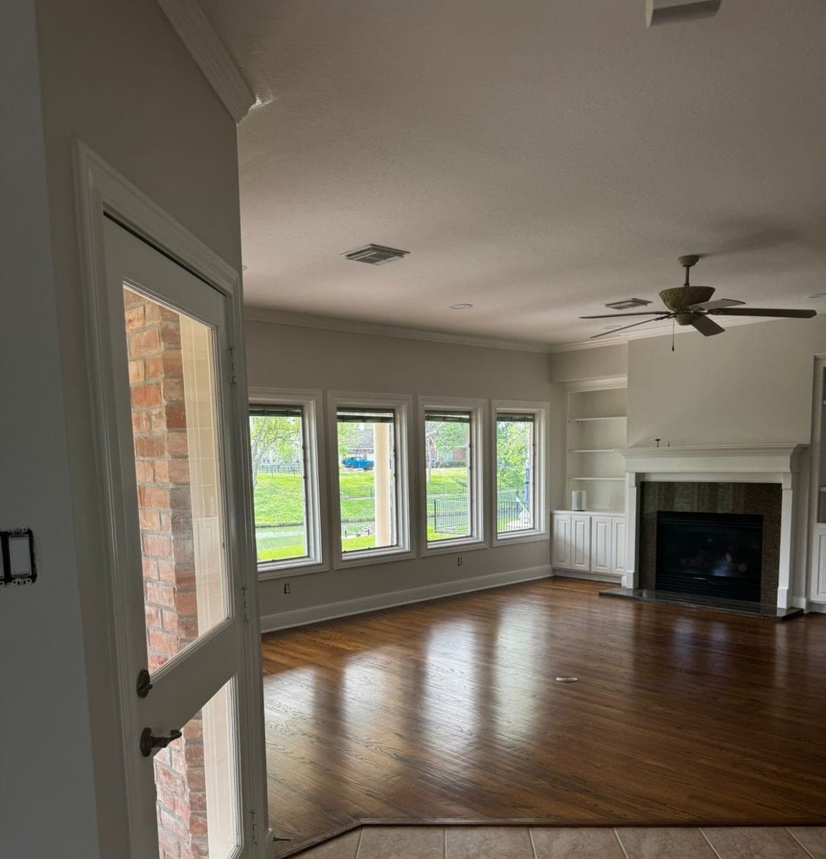 Family room with light gray walls, white trim around four windows and white built-ins beside the fireplace