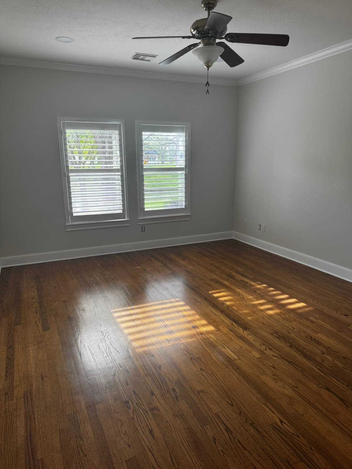 Bedroom with light gray walls, white crown molding, baseboards and window casings